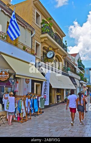 A view along Lithostroto, the main shopping street in the centre of the capital town, Argostoli. Young couple in shorts walking by. Stock Photo