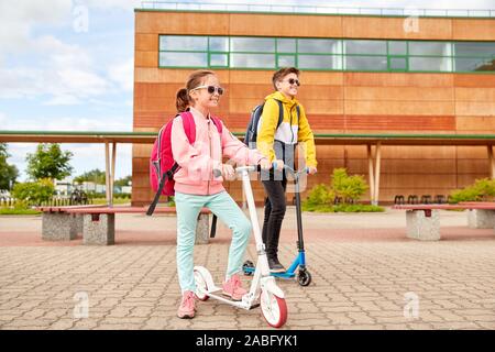 happy school children with backpacks and scooters Stock Photo