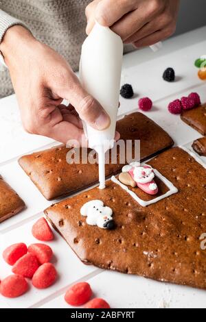 closeup of a caucasian man making a homemade gingerbread house, on a white table Stock Photo