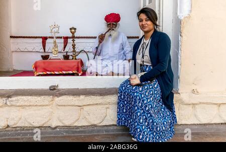 Mehrangarh Fort, Jodhpur, Rajasthan, India; 24-Feb-2019; an old man smoking hookah and a lady sitting in front Stock Photo