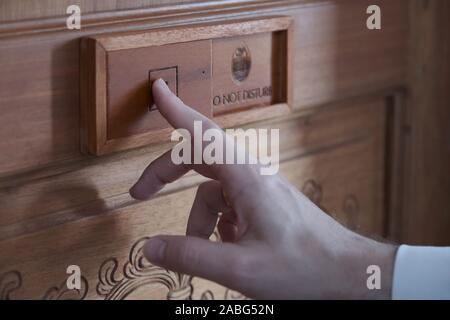 Man's hand on a plate located on the wooden door of the hotel room Stock Photo