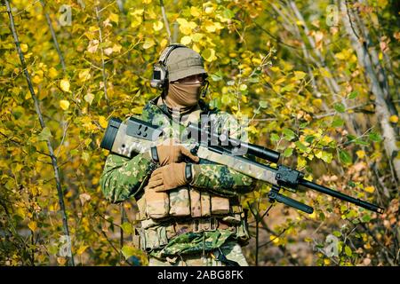 Airsoft man in uniform hold sniper rifle on yellow forest backdrop. Side  view Stock Photo - Alamy