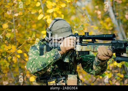 Airsoft man in uniform with sniper rifle, lurking in grass on forest  background. Vertical photo Stock Photo - Alamy
