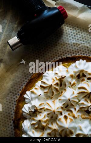 Lemon tart with french meringue caramelized on top, on a rustic table, french meringue caramelized with a food torch. Stock Photo