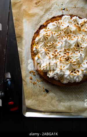 Lemon tart with french meringue caramelized on top, on a rustic table, french meringue caramelized with a food torch. Stock Photo