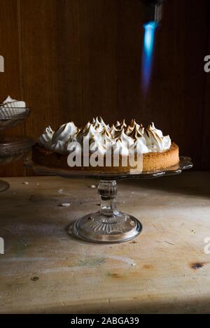 Lemon tart with french meringue caramelized on top, on a rustic table, french meringue caramelized with a food torch. Stock Photo