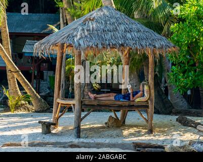 D'lagoon beach, Kecil, Perhentian Islands, Malaysia; May-2019; a old lady reading a book by the sea Stock Photo