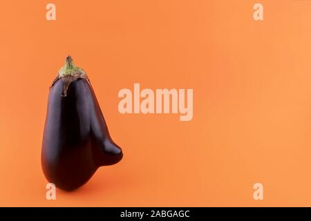 Ugly eggplant with a nose on a orange paper, minimalism Stock Photo