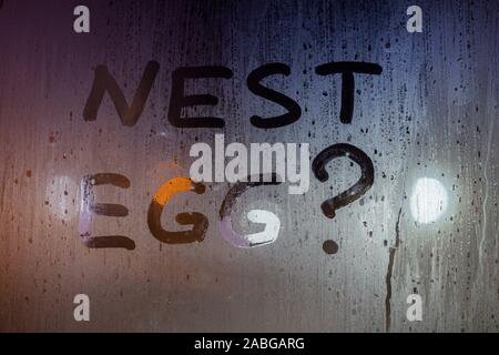 the question nest egg written by finger on night wet glass with blurred lights in background. Stock Photo