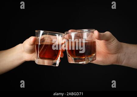 Male hands holds glasses of whiskey on black background, close up. Cheers Stock Photo