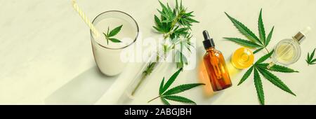 Cannabis milk, leaf of cannabis and a bottle of CBD Oil and tincture on the kitchen table. Top view, flat lay Banner Stock Photo