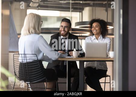 Smiling multiracial employers laugh talking with job candidate in office Stock Photo