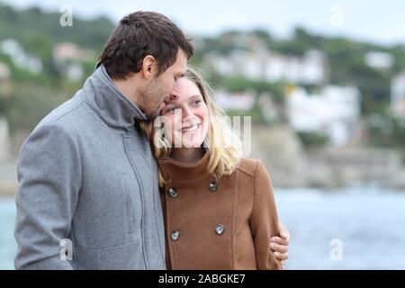 Happy couple in love flirting walking together on the beach in winter Stock Photo