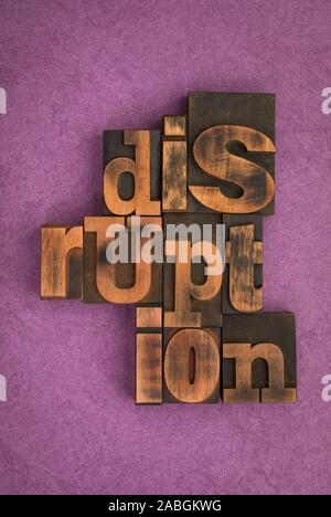 Disruption, single word written with vintage letterpress printing blocks on textured purple background. Stock Photo