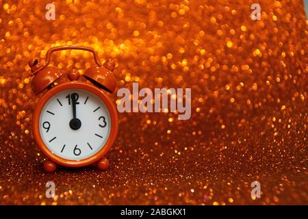 Golden clock to the left of the photo showing midnight on a golden background with a glitter. Copy space for advertising. Copy space area for text. Stock Photo