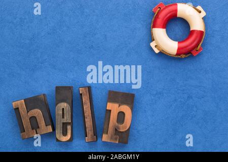 Support concept. Word help set with vintage letterpress type and life buoy on textured blue background with copy space Stock Photo