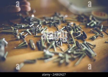different types and sizes of nails and screws on a wooden table Stock Photo