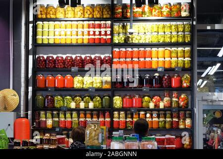 Fermented food concept. Variety glass jars of homemade pickled or fermented  colorful vegetables and jams on the shelves in the food shop. Stock Photo