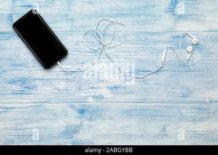 Smart phone with earphones on blue wooden background Stock Photo