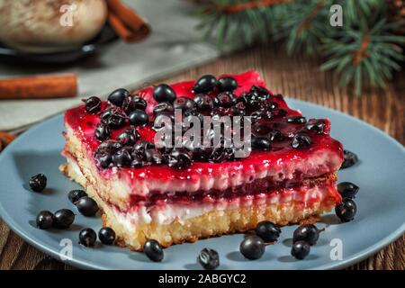 Slice of Christmas cheesecake with blackcurrant filling on a rustic wooden table