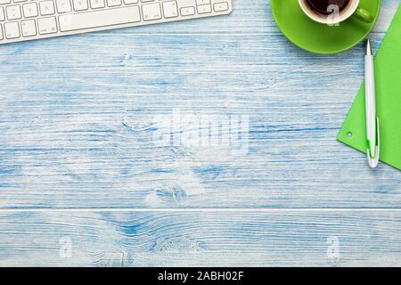 Background with computer keyboard,  coffee cup and utensils arranged on blue wooden desktop. Large copy space. Stock Photo