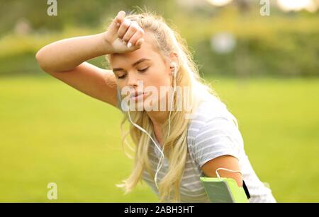 Tired female runner in the park taking a break - Sporty woman breathing and resting after outdoor sport activity Stock Photo