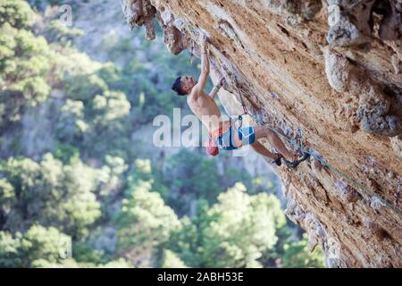 Young male rock climber on challenging route on overhanging cliff