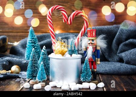 Christmas marshmallows, nutcracker and new year decorations on wood with grey plaid. Winter holidays Stock Photo