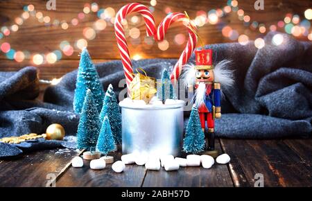 Christmas marshmallows, nutcracker and new year decorations on wood with grey plaid. Winter holidays Stock Photo