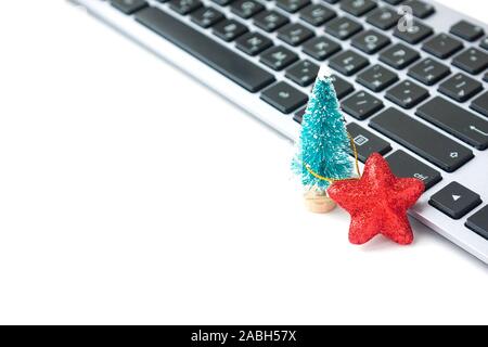 Small fir tree and red star near computer keyboard. Christmas mood in workplace. Work in New Year holidays Stock Photo