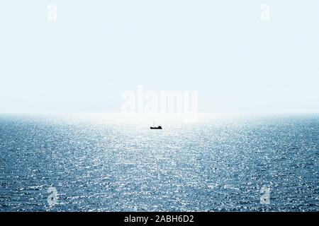 Lonely fishing ship trawler boat on ocean water. Calm clear sea sunny weather. Beautiful horizon of seascape Stock Photo