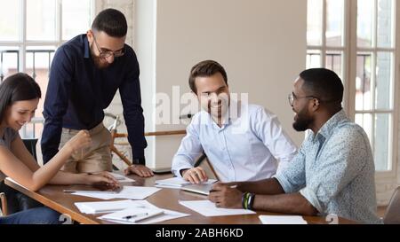 Happy mixed race colleagues laughing at jokes, having fun. Stock Photo