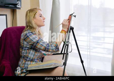 female designer draws an illustration on an easel Stock Photo