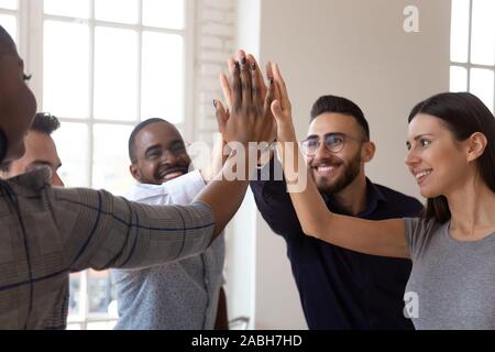 Overjoyed multiracial young business team members giving high five Stock Photo