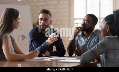 Concentrated young mixed race business partners discussing development strategy. Stock Photo