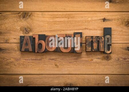 About me, phrase written with vintage letterpress printing blocks on rustic wood background. Stock Photo