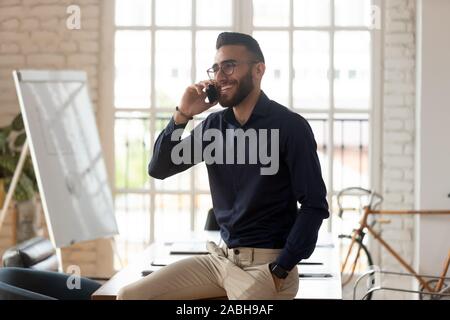 Happy young arabian male manager talking on mobile phone. Stock Photo
