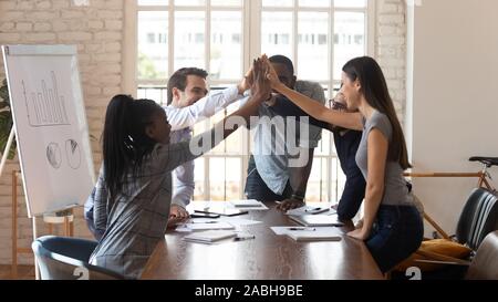 Euphoric mixed race team giving high five to each other. Stock Photo