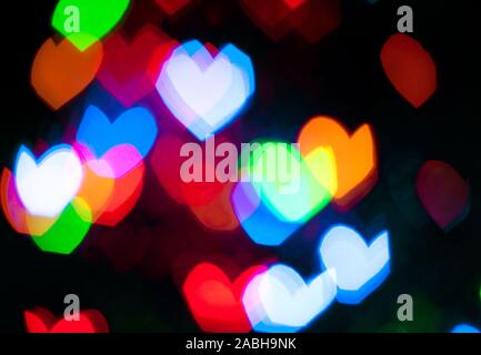 Glowing and festive colored light hearts created from in camera and lens bokeh. Christmas fairy lights defocused giving a blurred effect. Background f Stock Photo