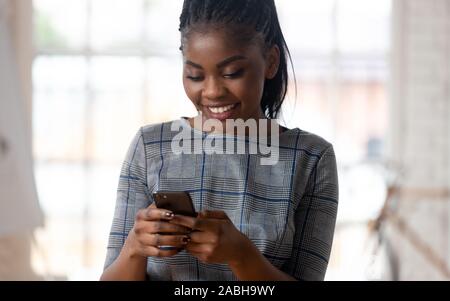 Smiling young african american business lady holding smartphone. Stock Photo