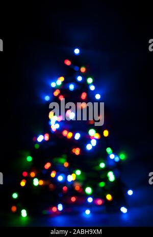 Glowing and festive colored light circles created from in camera and lens bokeh. Christmas fairy lights defocused giving a blurred effect. Background Stock Photo