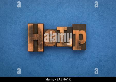 Help, single word written with vintage letterpress printing blocks on textured blue background. Stock Photo