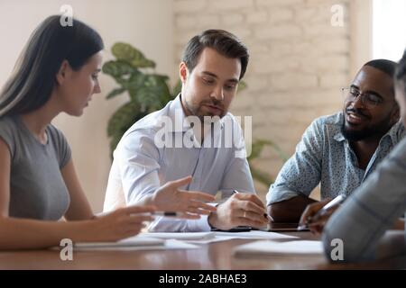 Financial expert holding brainstorming meeting with multiracial engaged colleagues. Stock Photo