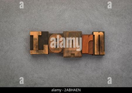 Learn, single word written with vintage letterpress printing blocks on textured grey background. Stock Photo