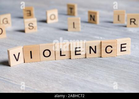 Word made of wooden letters - violence, on a gray background with cubes. Crime designation concept. Close up. Stock Photo