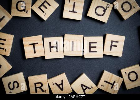 Word made of wooden letters - thief, on black. Crime designation concept. Top view. Stock Photo