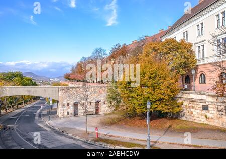 Budapest, Hungary - Nov 6, 2019: Beautiful street in the historical old town of Hungarian capital city photographed with autumn trees. Historical buildings, road, no people. Eastern European town. Stock Photo