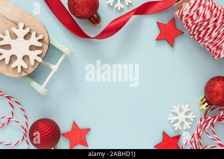 Christmas background, winter decorations - ribbon bow, sleigh, baubles, snowflakes over blue background, with copy space Stock Photo