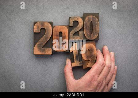 New year 2020 concept with vintage letterpress printing blocks. Hand replacing number 19 with number 20 Stock Photo