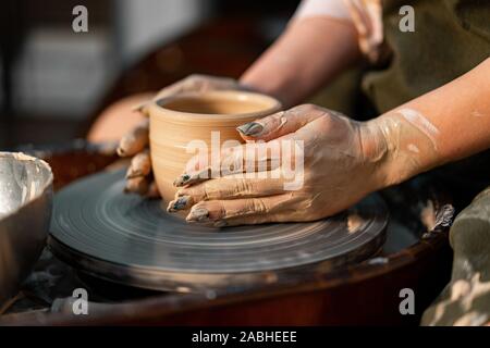 Woman Potter Hands Shaped Mug From Clay. The Process of Creating Pottery On a Potter's Wheel. The Master Working In Ceramics Studio Stock Photo